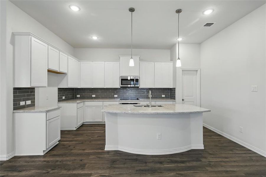 Kitchen with a sink, light stone counters, stainless steel microwave, and visible vents Kitchen with a sink, light stone counters, stainless steel microwave, and visible vents