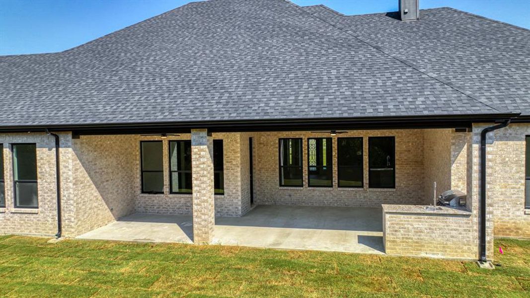 Rear view of property with a lawn and a patio