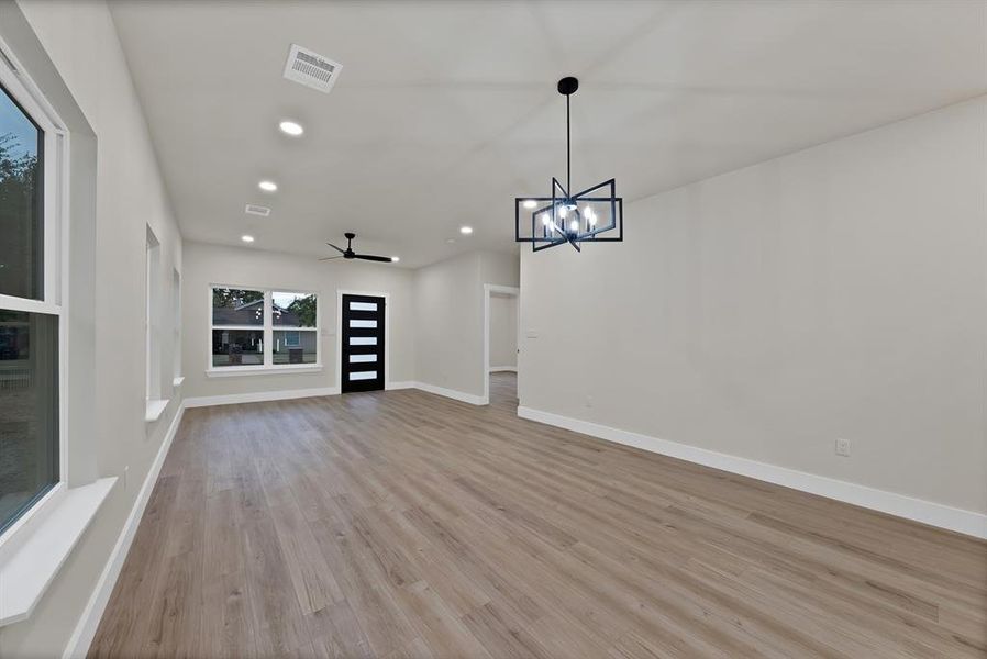 Unfurnished living room featuring recessed lighting, light wood-style floors, ceiling fan, and a chandelier