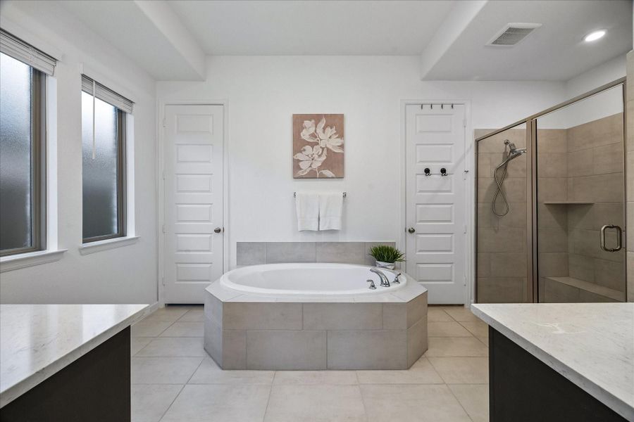 Enjoy a daily dose of luxury in this spa-like ensuite with a deep soaking tub, separate walk-in shower with a bench, separate vanities, a massive walk-in closet, and a private water closet.