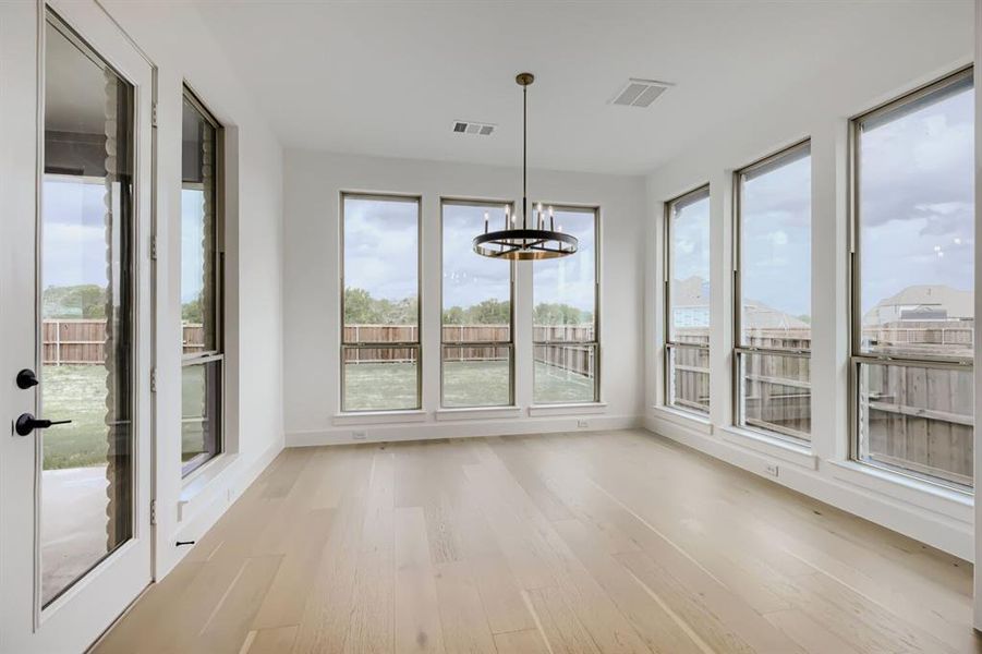 Unfurnished sunroom featuring wood finished floors, healthy amount of natural light, and a chandelier
