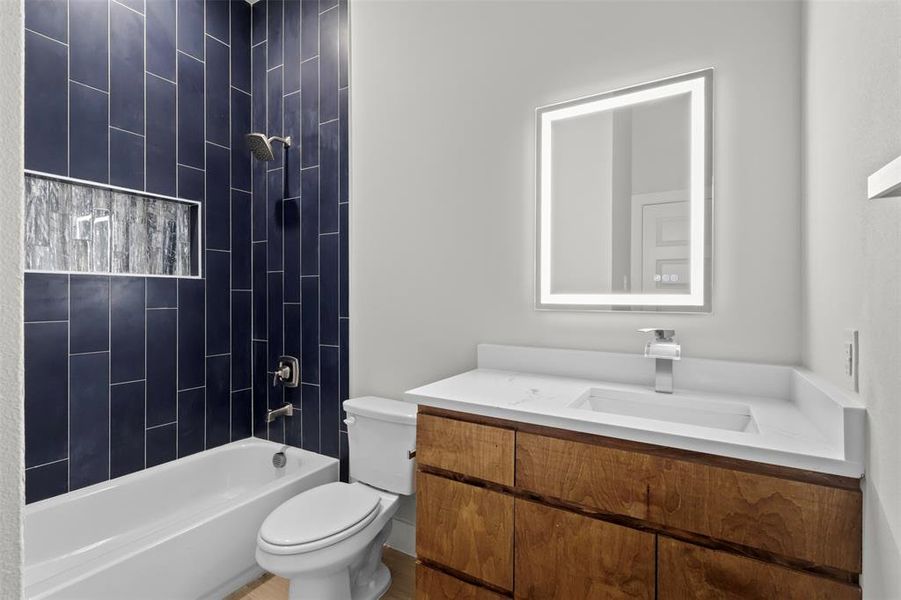 Full bathroom with tiled shower / bath combo, toilet, and vanity