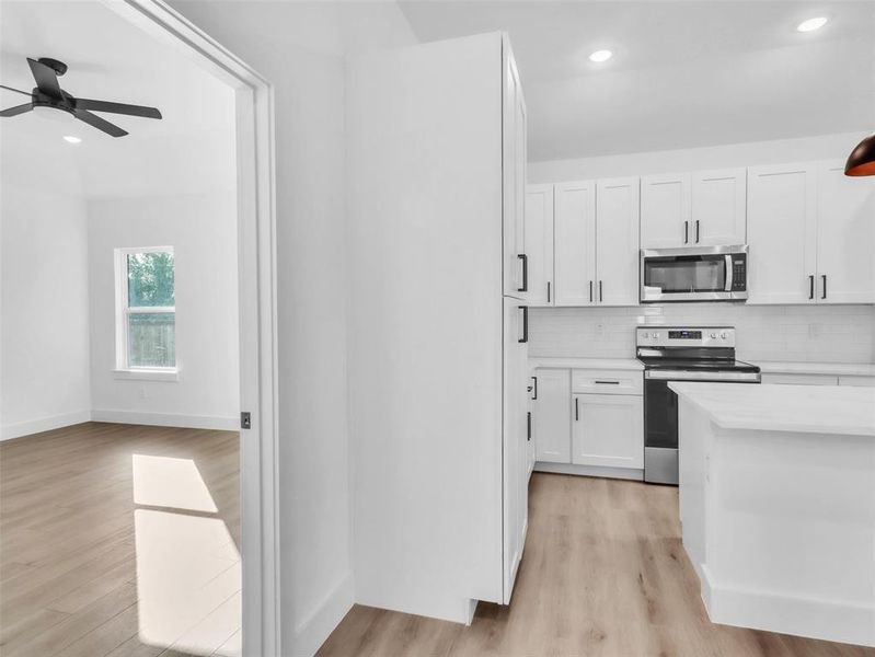 Kitchen with white cabinets, light countertops, tasteful backsplash, appliances with stainless steel finishes, and ceiling fan Kitchen with white cabinets, light countertops, tasteful backsplash, appliances with stainless steel finishes, and ceiling fan