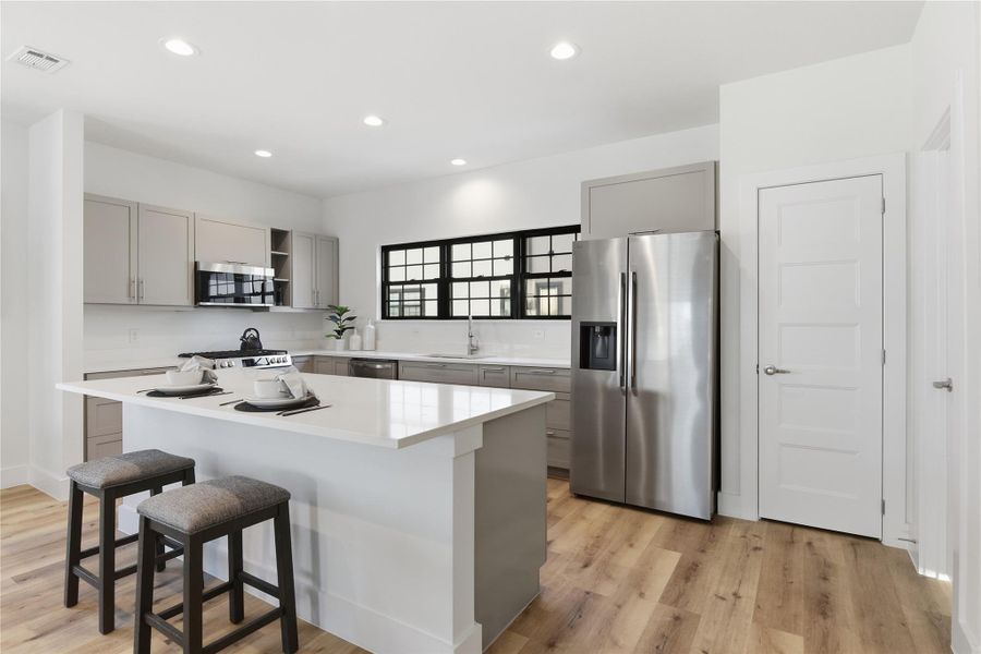 This modern kitchen features sleek stainless steel appliances, a spacious island with seating, and stylish cabinetry.