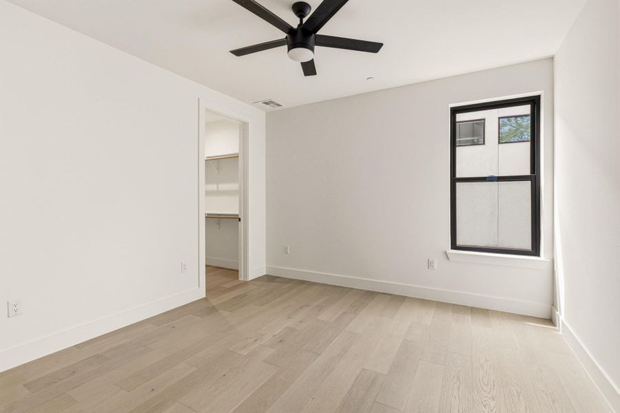 Bright room with wood-finish flooring, a black ceiling fan, and a black-framed window