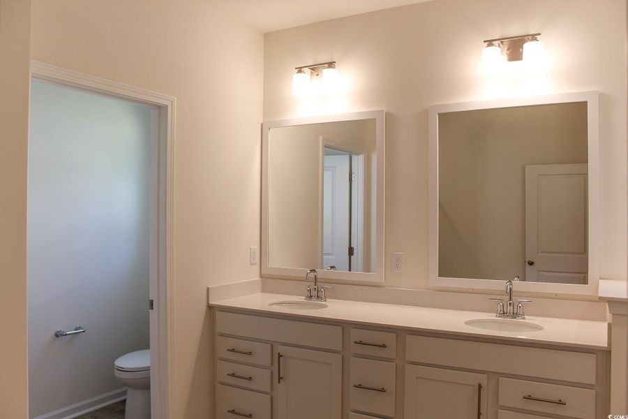Full bathroom with double vanity and toilet