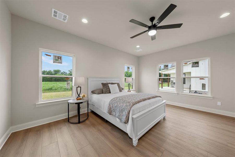 Spacious room featuring wood-finish flooring, vaulted ceiling, and multiple windows