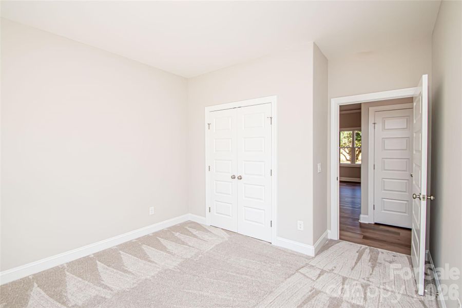 Spacious Bedroom #4 with plush carpet, large closet, oversized window, and convenient outlet ready for ceiling fan installation.