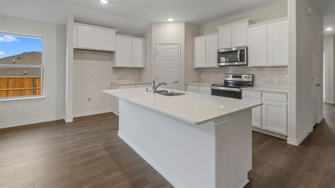 Kitchen with white cabinetry, stainless steel appliances, an island with sink, dark wood-style floors, and recessed lighting Kitchen with white cabinetry, stainless steel appliances, an island with sink, dark wood-style floors, and recessed lighting