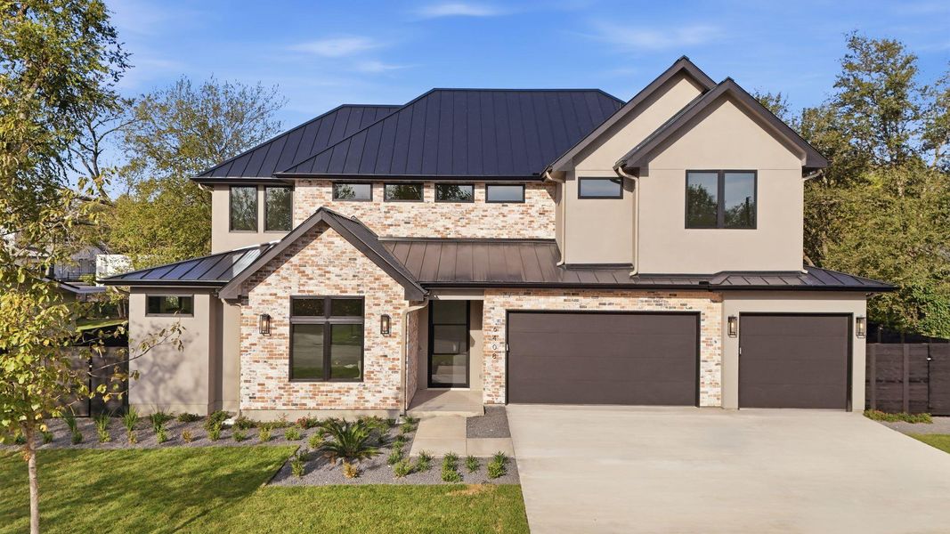 View of front facade featuring a standing seam roof, a metal roof, a garage, and concrete driveway View of front facade featuring a standing seam roof, a metal roof, a garage, and concrete driveway