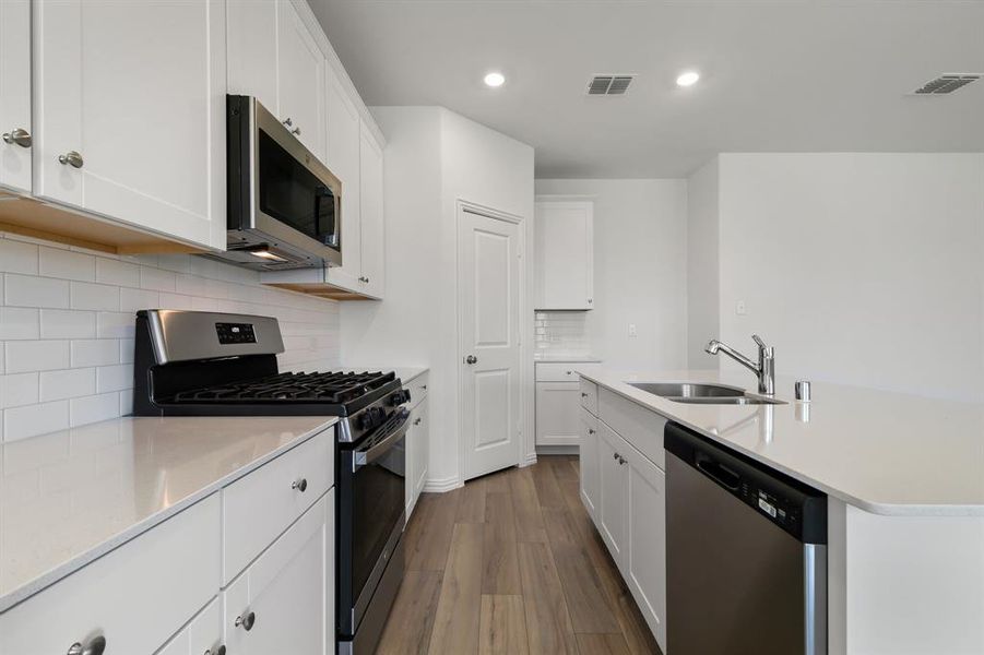 Kitchen featuring dark hardwood / wood-style flooring, white cabinetry, backsplash, appliances with stainless steel finishes, and sink