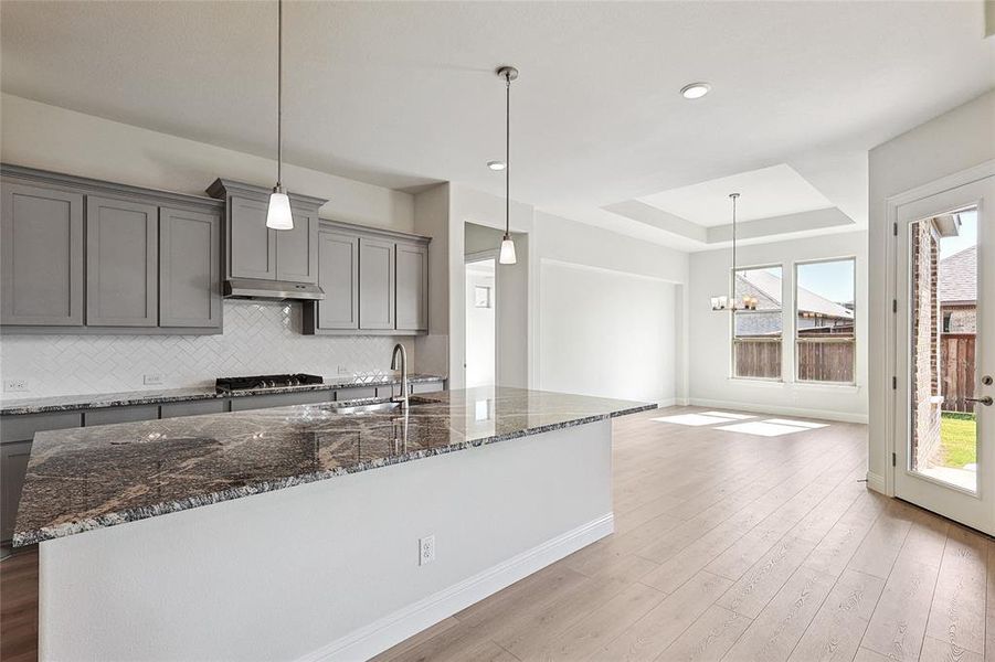 Kitchen with sink, stainless steel gas cooktop, pendant lighting, and light wood-type flooring