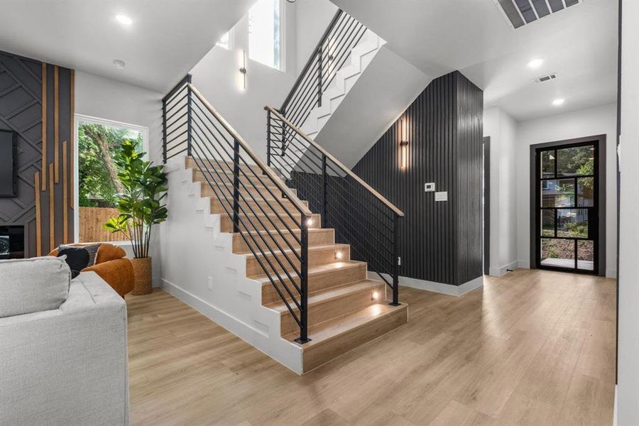 Foyer with recessed lighting, light wood-style flooring, a fireplace, and a high ceiling
