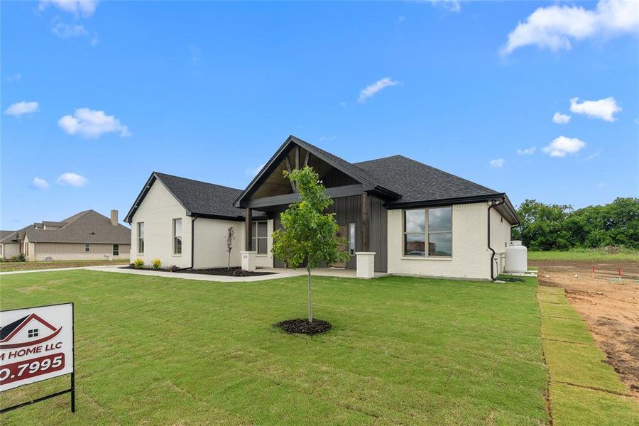 View of front facade featuring a front yard and a shingled roof