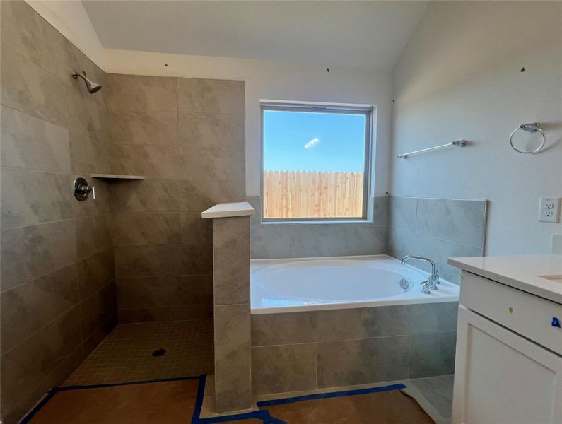 Full bathroom featuring vanity, a bath, a tile shower, and lofted ceiling