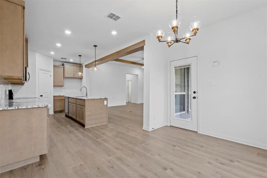 Kitchen featuring light wood-type flooring, hanging light fixtures, sink, and an island with sink