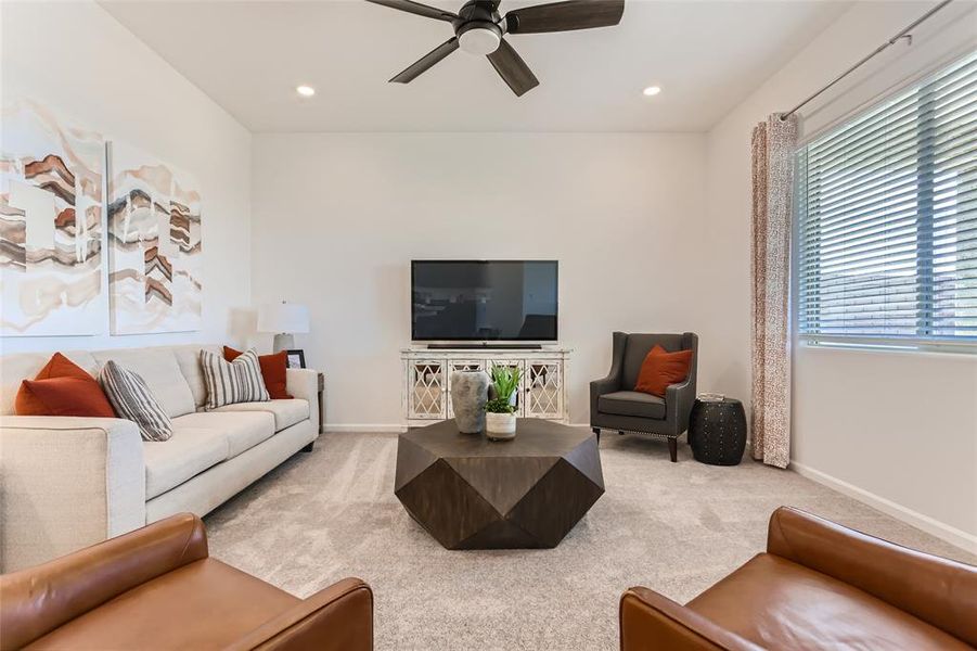 Carpeted living room featuring ceiling fan and recessed lighting