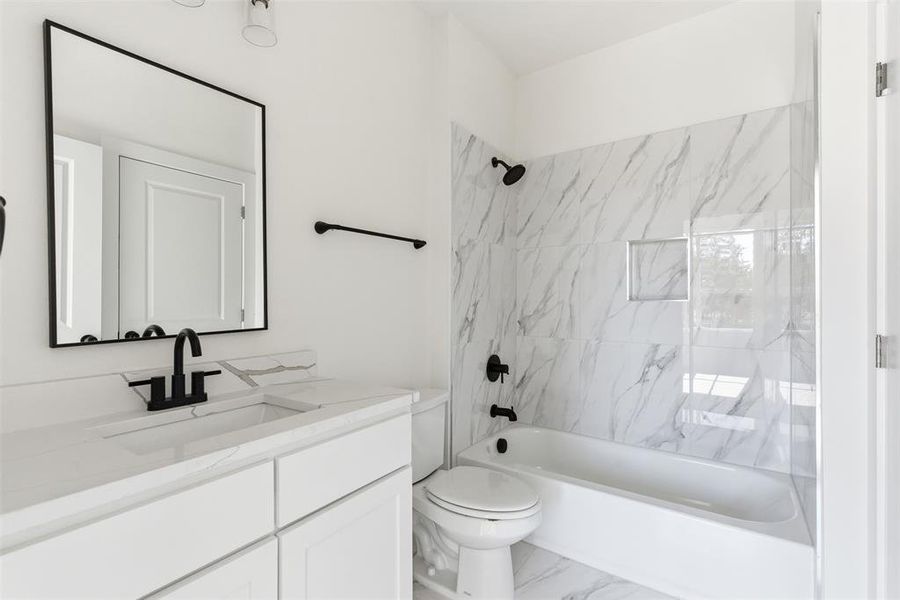 Bathroom featuring shower / bathtub combination, vanity, and marble look tiles Bathroom featuring shower / bathtub combination, vanity, and marble look tiles