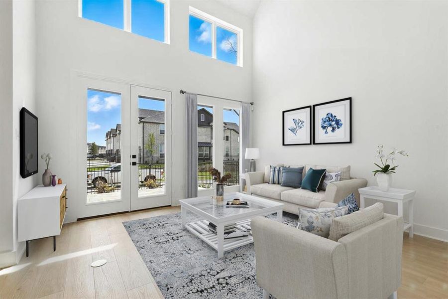 Living room with a high ceiling, french doors, and light wood-style floors Living room with a high ceiling, french doors, and light wood-style floors