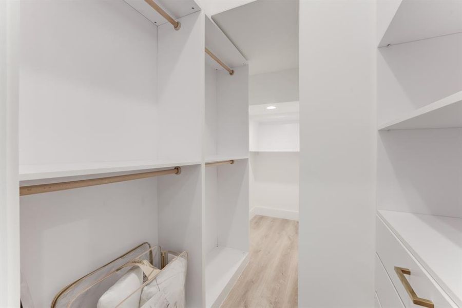 Stunning designer walk-in closet with built in drawers, storage space, and hanging rods for clothes.