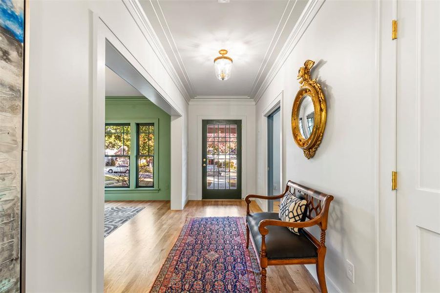 Foyer entrance with crown molding and wood-type flooring