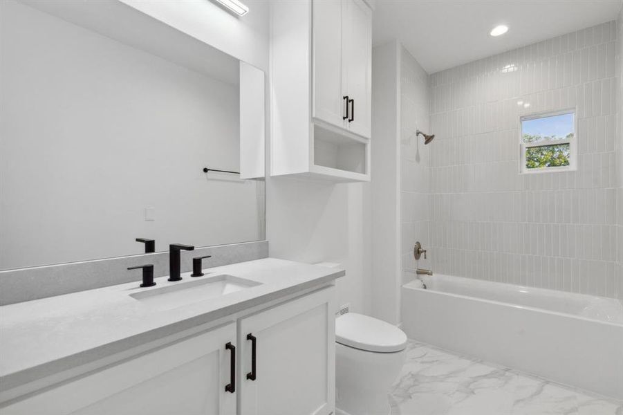 Full bathroom featuring vanity, tiled shower / bath combo, and toilet