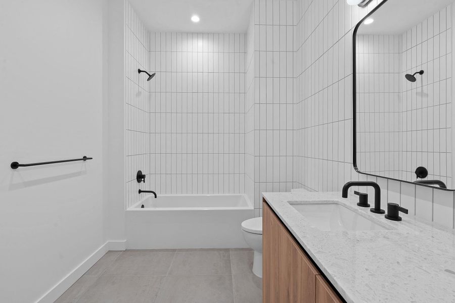 Full bath with light tile patterned flooring, washtub / shower combination, vanity, tile walls, and recessed lighting