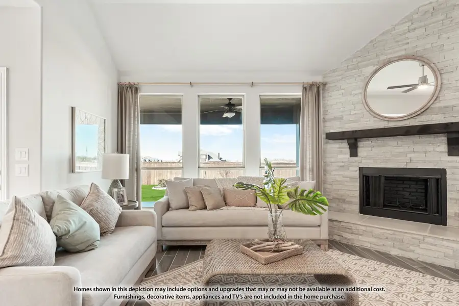 Living room with stone fireplace, neutral sofas, vaulted ceiling, and large windows overlooking backyard Living room with stone fireplace, neutral sofas, vaulted ceiling, and large windows overlooking backyard