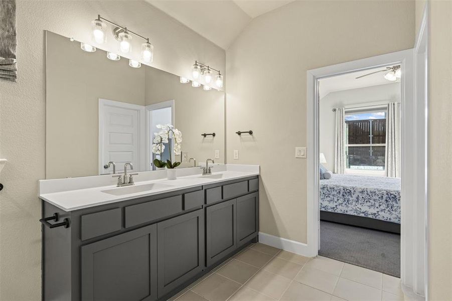 Ensuite bathroom with lofted ceiling, ensuite bath, a sink, and tile patterned floors