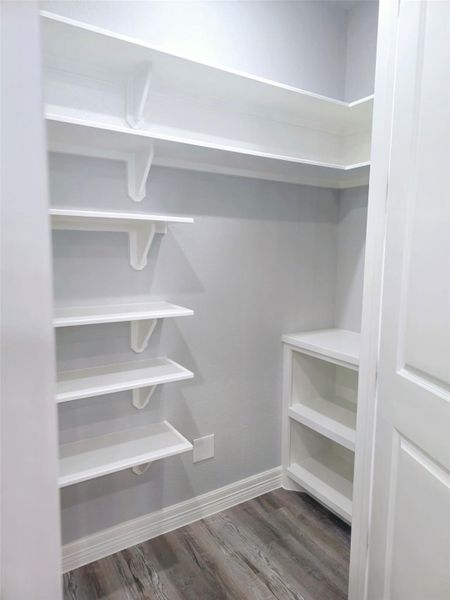 Walk-in pantry featuring multiple white shelves.
