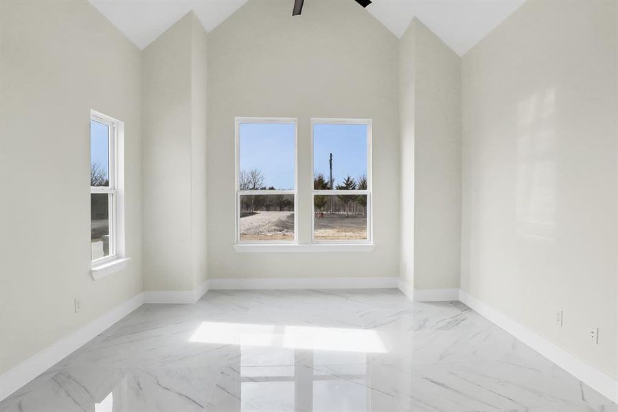 Spare room with ceiling fan and high vaulted ceiling