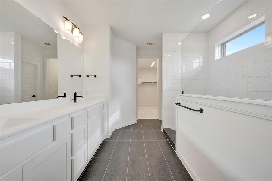 Bathroom featuring a spacious closet, double vanity, walk in shower, dark tile patterned flooring, and recessed lighting