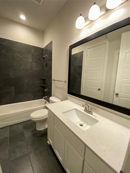 Bathroom featuring vanity, tub / shower combination, and dark tile patterned flooring Bathroom featuring vanity, tub / shower combination, and dark tile patterned flooring