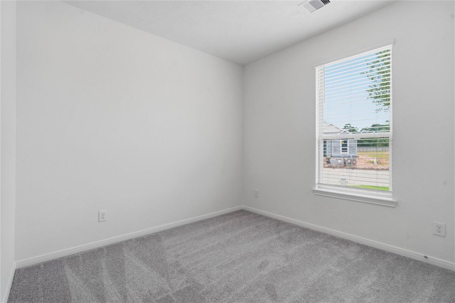 Tucked peacefully in the front of the home is this secondary bedroom! It offers comfort and style with plush carpeting, neutral paint tones, recessed lighting, a large window with blinds, and an ample sized closet.