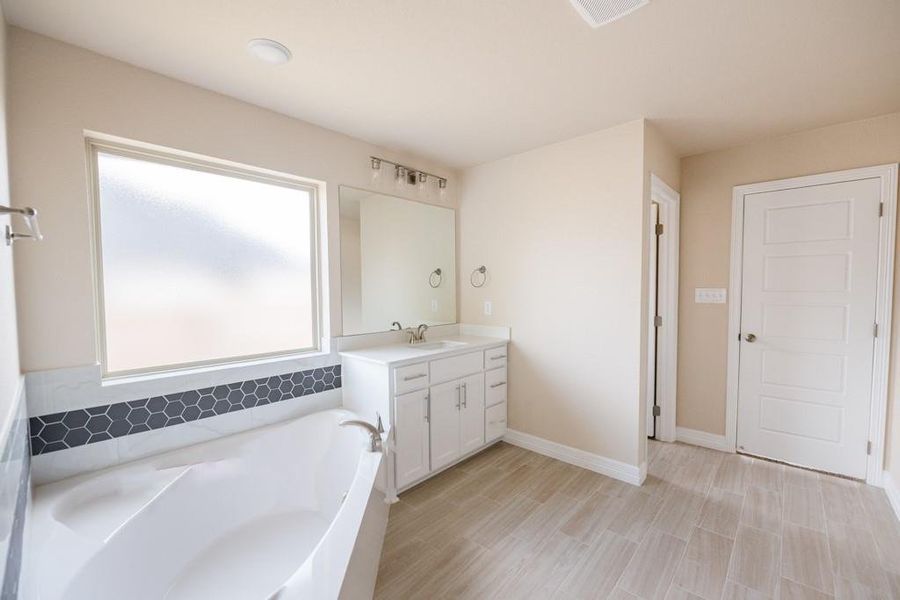 Full bathroom with vanity, a garden tub, and wood finish floors Full bathroom with vanity, a garden tub, and wood finish floors