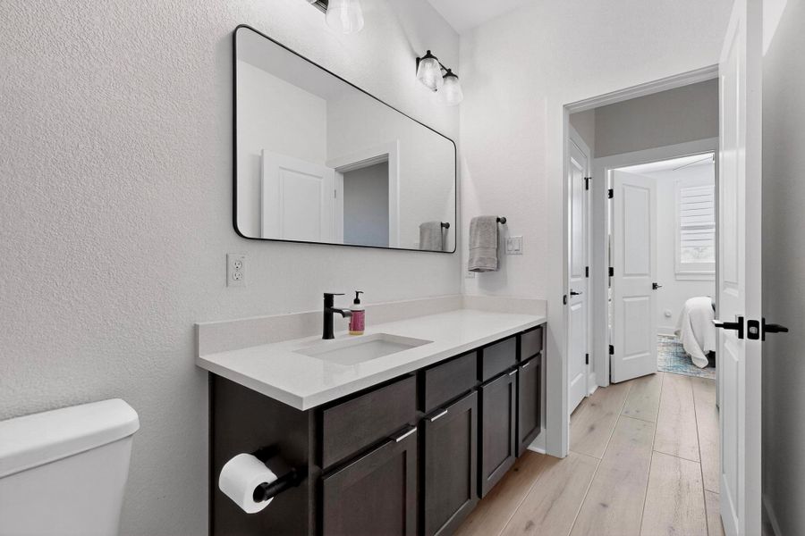 Bathroom with light wood-type flooring, vanity, and a textured wall