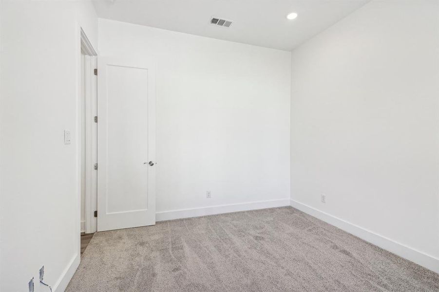 Empty room with light colored carpet and recessed lighting