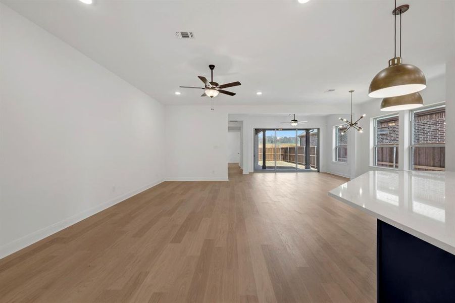 Unfurnished living room with light wood-style floors, a chandelier, and ceiling fan