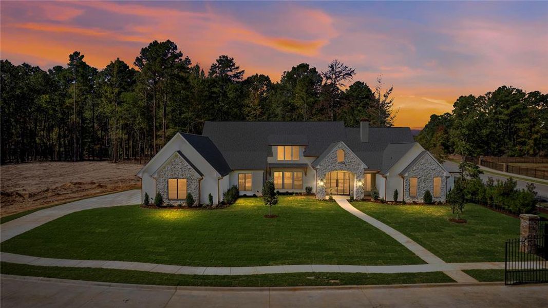 French country style house featuring stone siding, a front lawn, driveway, and a chimney