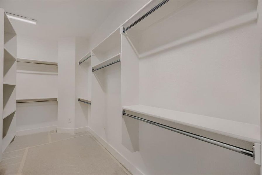 Walk-in closet featuring white built-in shelving, multiple hanging rods, and recessed lighting