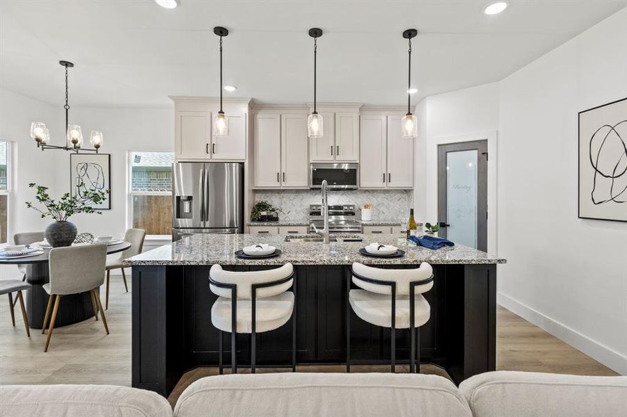 Kitchen with stainless steel appliances, tasteful backsplash, a breakfast bar, and a center island with sink