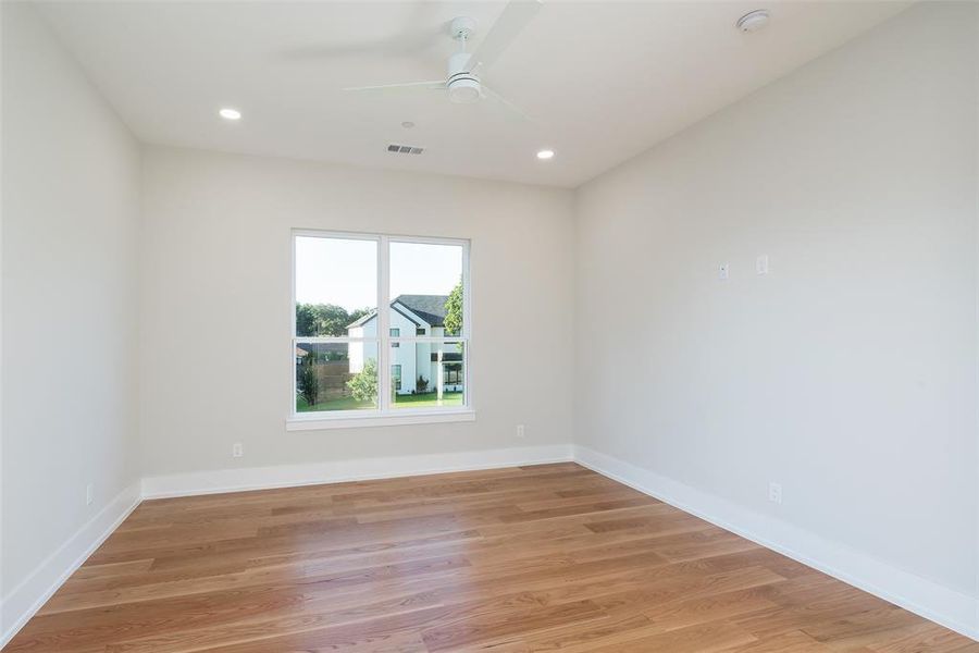 Empty room with ceiling fan and light hardwood / wood-style floors