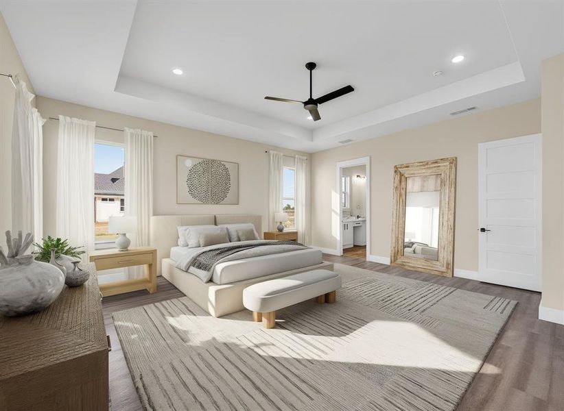 Staged Bedroom featuring a raised ceiling, ensuite bathroom, wood finished floors, a ceiling fan, and recessed lighting Staged Bedroom featuring a raised ceiling, ensuite bathroom, wood finished floors, a ceiling fan, and recessed lighting