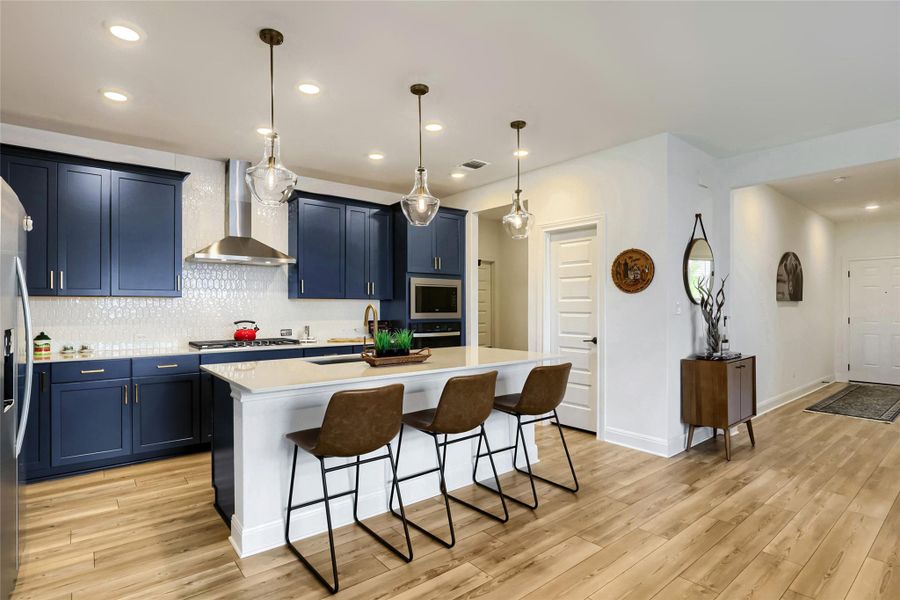 A contemporary kitchen features rich blue cabinetry, light wood flooring, and an inviting island with pendant lighting. A contemporary kitchen features rich blue cabinetry, light wood flooring, and an inviting island with pendant lighting.