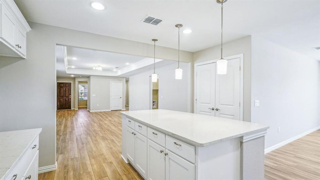 Kitchen featuring white cabinetry, decorative light fixtures, light wood-style flooring, a center island, and recessed lighting Kitchen featuring white cabinetry, decorative light fixtures, light wood-style flooring, a center island, and recessed lighting