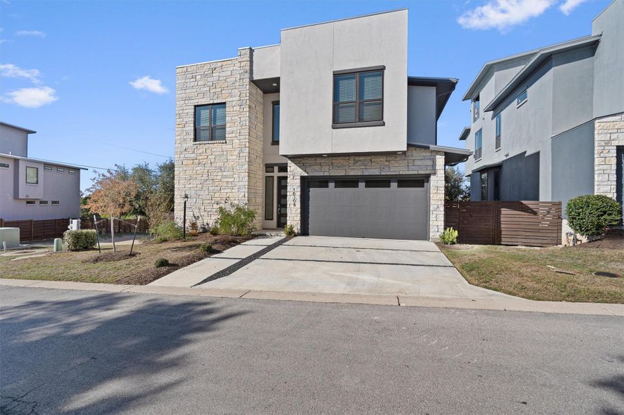 Contemporary home with stone siding, stucco siding, concrete driveway, and an attached garage Contemporary home with stone siding, stucco siding, concrete driveway, and an attached garage