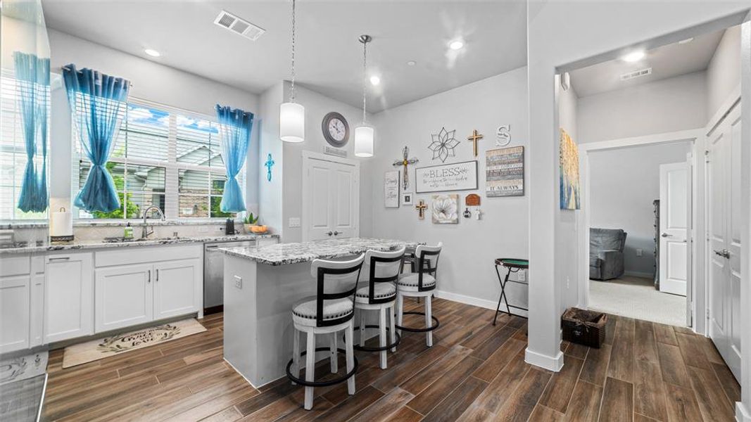 Kitchen featuring decorative light fixtures, a healthy amount of sunlight, white cabinets, and a kitchen island