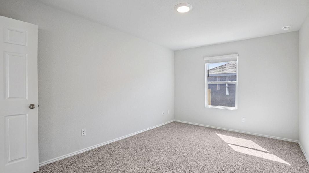 A well-lit bedroom features plush carpeting, a single window, and a modern recessed light fixture. A well-lit bedroom features plush carpeting, a single window, and a modern recessed light fixture.