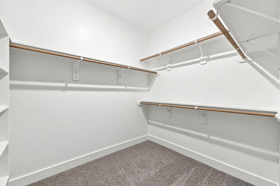 Spacious primary walk-in closet with extensive built-in shelving and hanging space. Spacious primary walk-in closet with extensive built-in shelving and hanging space.