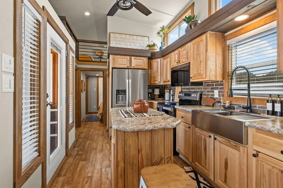 Kitchen with plenty of natural light, appliances with stainless steel finishes, vaulted ceiling, backsplash, and dark wood-style flooring